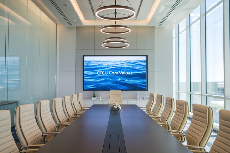 Image of a sleek, modern conference room with discreet ceiling microphones and an integrated video display.