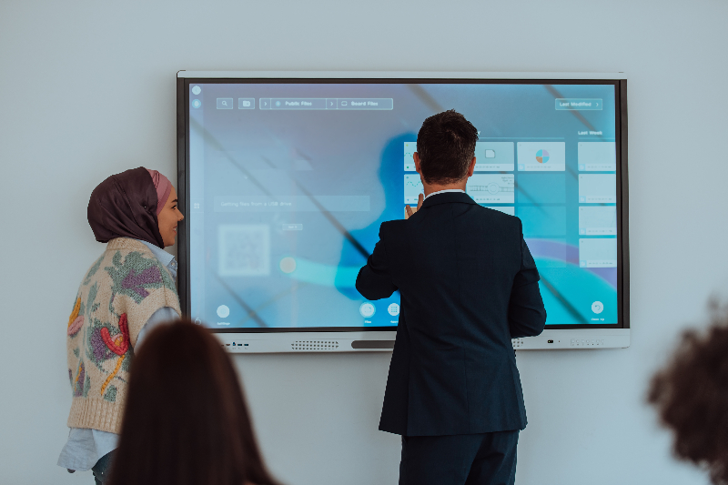 Close-up shot of a modern touch panel displaying a simplified user interface for an AV Control System in a conference room.