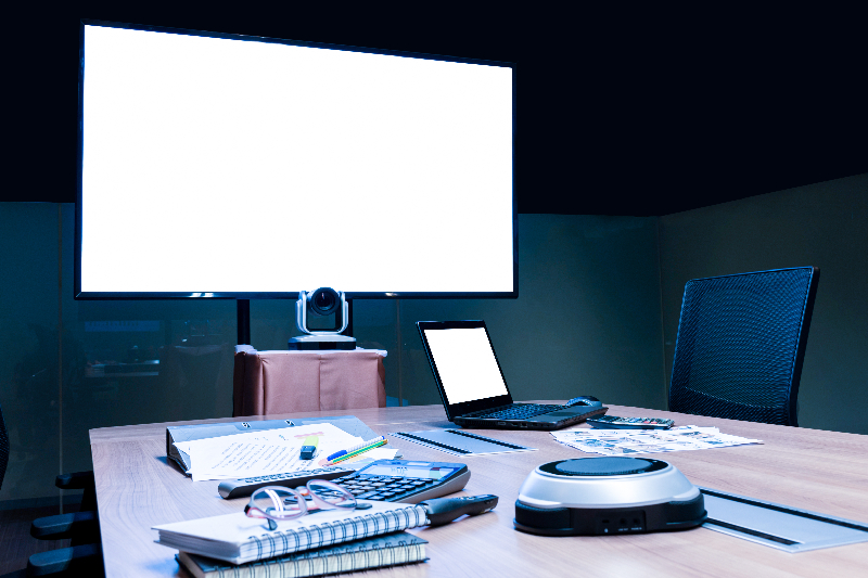 Image of a compact, all-in-one video bar mounted below a monitor in a small huddle room
