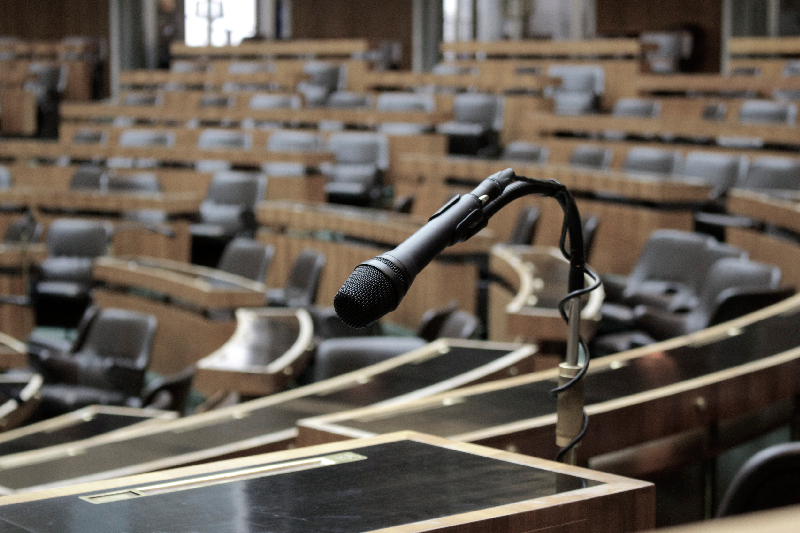 Image of a Shure delegate microphone unit with gooseneck mic, situated on a conference table.