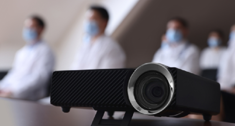 Front view of the Bronx BR-MTC12X teacher tracking camera active on a wall bracket inside a modern lecture room.